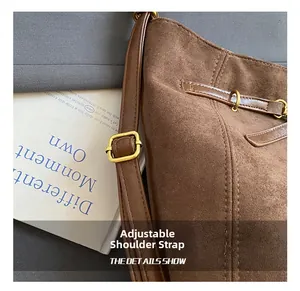 Detail of brown suede tote bag with adjustable leather strap and golden metal buckle