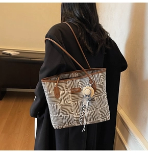 Detail of a large canvas tote with white bone pattern and brown leather trim on a model
