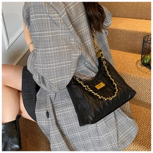 Detail of black V-quilted faux leather shoulder bag with gold chain and turn-lock