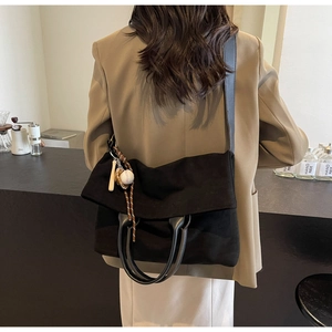 Detail view of large black tote bag with shoulder strap and baseball bat pendant charm