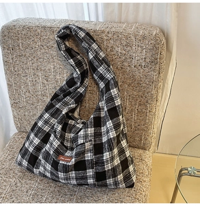 Detail shot of black and white checkered canvas tote bag with brown leather label on sofa