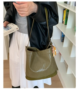 Sac seau tissé vert olive avec breloque en perles sur une étagère blanche