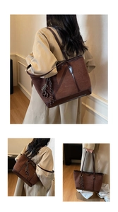 Detail of a brown suede and leather tote bag featuring tassels and metal hardware