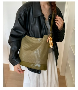 Détails du sac seau tressé vert olive avec pompon en perles de bois et cuir lisse de qualité