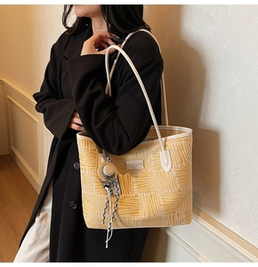 Close-up of bright yellow textured tote bag with logo detail and white leather strap