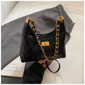 Close-up of black quilted tote bag featuring a gold chain strap and metallic twist lock