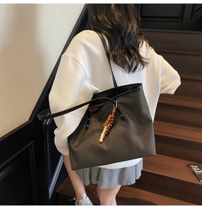 Large black tote bag with wooden bead charm shown on shoulder for a minimalist look