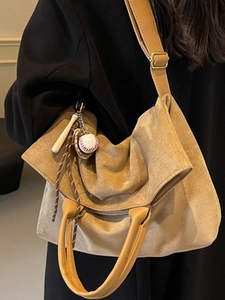 Large khaki tote bag in suede texture with baseball charm on a model's shoulder