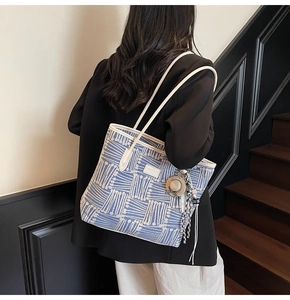 Detail of blue tote bag with white geometric stripes worn over the shoulder by a model