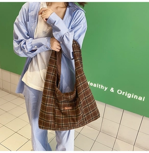Detailed view of brown plaid canvas tote bag with front pocket and vintage letter patch