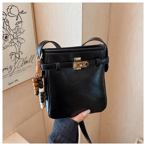 Detailansicht der schwarzen Eimertasche mit Litschi-Muster, Schloss und Perlenanhänger