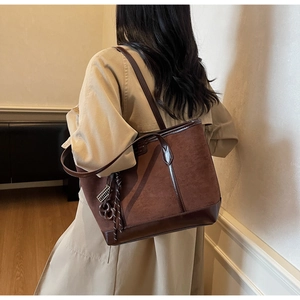 Detailed side view of a large vintage brown suede tote bag with contrast leather trim