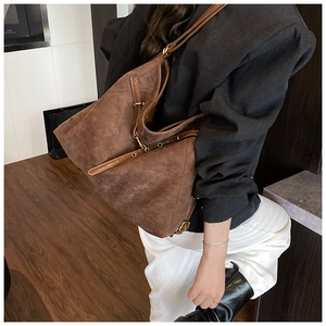 Detail of a brown suede hobo tote bag showing adjustable strap and vintage metal hardware