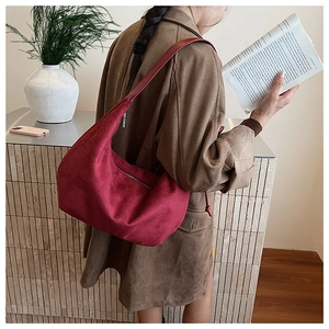 Detailed view of the burgundy suede moon-shaped hobo bag shoulder strap and zipper