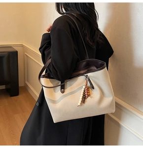 Chic beige canvas tote bag with brown leather trim and wooden bead charm accessory