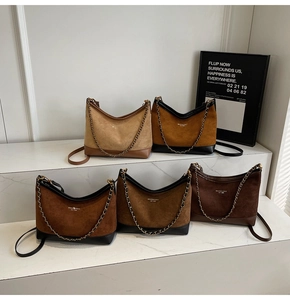 Macro view of five suede shoulder bags in different shades of brown with metal chain straps