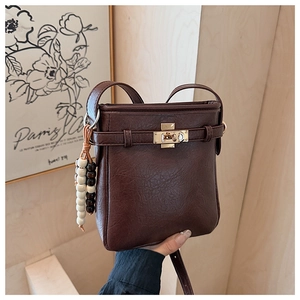 Detailansicht der schokobraunen Eimertasche mit Litschi-Textur und Metalldrehverschluss