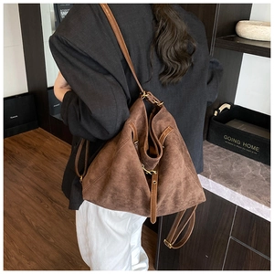 Detail of a brown suede bucket bag with drawstring closure and vintage brass hardware