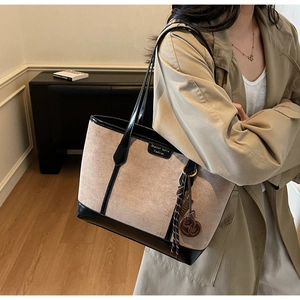 Detail of contrast-stitched khaki suede tote bag with black leather straps and brand label