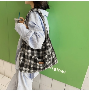 Close-up of black and white checkered canvas tote bag with a premium leather label