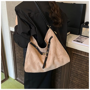 Detail of a large camel suede tote bag with black leather trim and golden hardware buckle