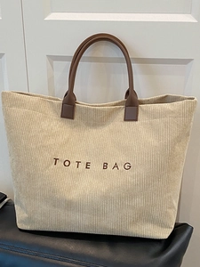 Minimalist beige corduroy tote bag with brown leather handles and embroidered text