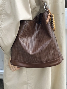 Sac seau tressé marron avec texture complexe et détail de breloque en perles bohème