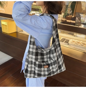 Close-up of black and white checkered canvas tote bag with a leather patch detail