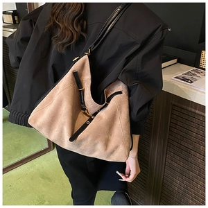Detail view of khaki suede tote bag with black leather trim and metal lock closure