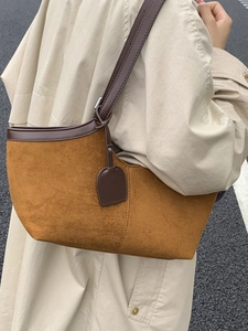 Brown faux suede tote bag with leather trim carried by a model in a beige trench coat