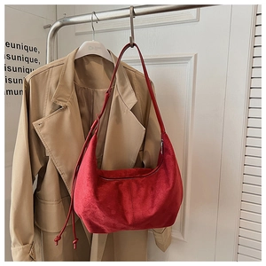 Detail of red suede crescent bag with knot strap and smooth zipper closure