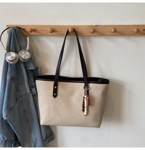 Detailed close-up of a minimalist two-tone tote bag hanging on a wooden wall hook