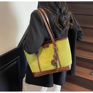 Detail of green suede tote bag with brown leather straps and woven cord accents