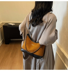 Close-up of vintage suede and black leather patchwork shoulder bag with gold chain strap