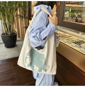 Detail of canvas tote bag with artistic green elephant print in a natural cafe setting