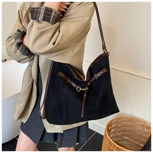 Close-up of black suede tote bag with brown leather strap and gold horsebit hardware