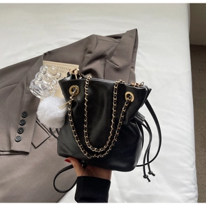 Close-up of black leather drawstring bucket bag with gold chain and white fur charm