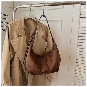 Detail of dark brown faux suede dumpling bag with textured surface and shoulder strap