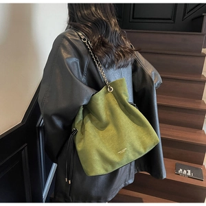 Sac seau vert tendance avec cordon et chaîne porté par une femme en veste de cuir