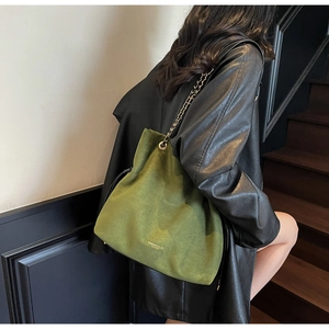 Détail du sac seau en daim vert foncé avec chaîne dorée et inscription tendance