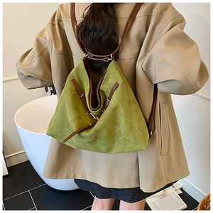 Detail view of olive green faux suede backpack with brown leather straps on a model
