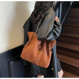 Vue détaillée d'un sac seau en daim marron avec chaîne dorée et cordons noirs élégants