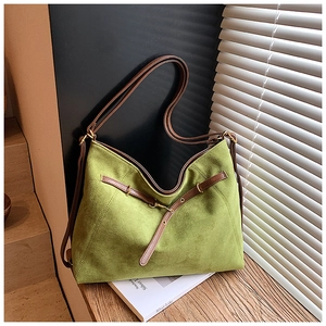 Detail view of grass green suede tote bag with brown leather straps on wooden stairs