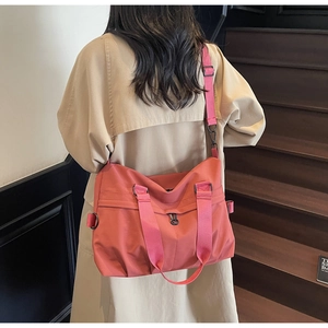 Rear view of a model carrying a large coral pink nylon tote bag on a wooden staircase
