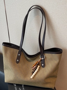 Minimalist khaki canvas tote bag with brown faux leather handles and beaded charm
