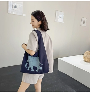 Artistic detail of a navy canvas tote bag with a light blue elephant print in a minimalist gallery