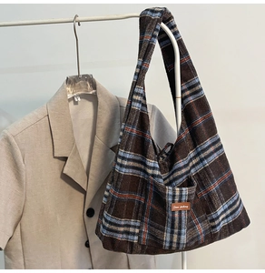 Detail of retro brown checkered canvas tote bag with side pocket and leather label