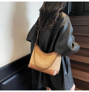 Detail of retro brown suede half-moon shoulder bag styled with black leather jacket