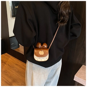 Détail du mini sac bandoulière à motif pomme porté par un mannequin en situation réelle