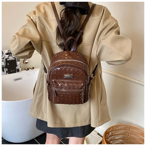 Détail d'un sac à dos en cuir tressé marron foncé avec fermetures éclair argentées